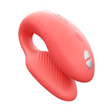 We-Vibe Chorus couple’s vibrator in coral. A small, adjustable, horseshoe shaped toy with one end slightly larger than the other. One button control on the larger end. Remote control has 4 buttons.