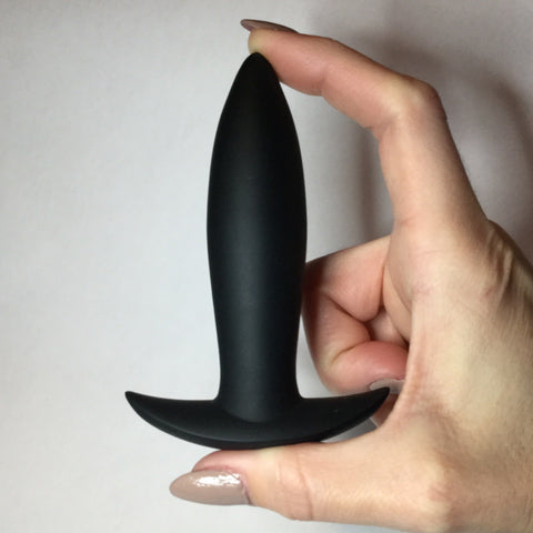 A slim black anal plug with tapered tip and curved, flared base