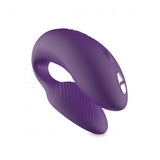 We-Vibe Chorus couple’s vibrator in pink. A small, adjustable, horseshoe shaped toy with one end slightly larger than the other. One button control on the larger end. Remote control has 4 buttons.