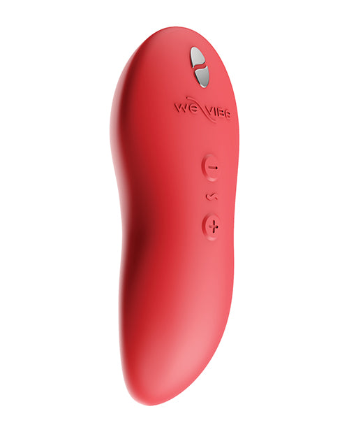 We-Vibe Touch X vibrator in coral. A palm-sized vibe with a slightly curved, pointed tip. Below the tip, on the front side, is a slightly concave spot for less direct contact. Three button controls on the back side. there are slight grooves on the sides at the midpoint.